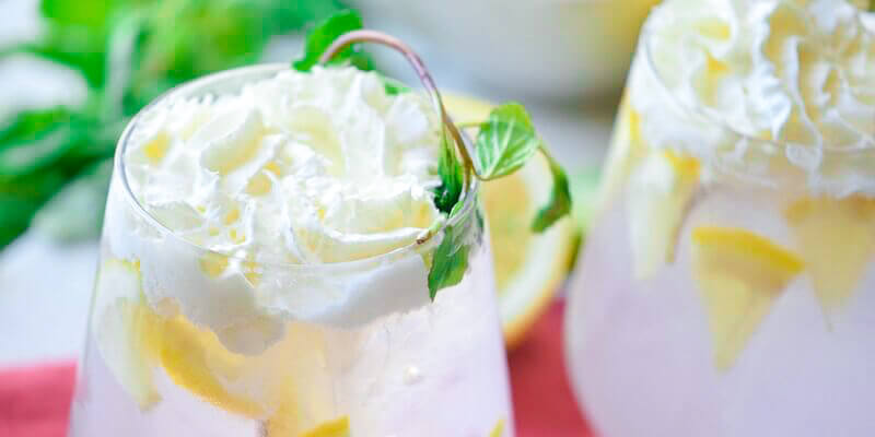 fizzy lemonade in glasses with whipped cream and lemons