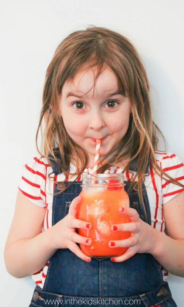 little girl drinking fruit punch in a mason jar