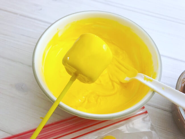 dipping marshmallow pops in yellow chocolate