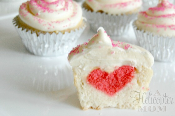 white cupcake cut in half to reveal a red heart inside.