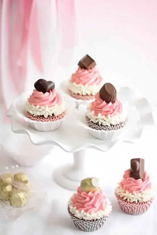 pink frosted cupcakes topped with chocolate bon buns.