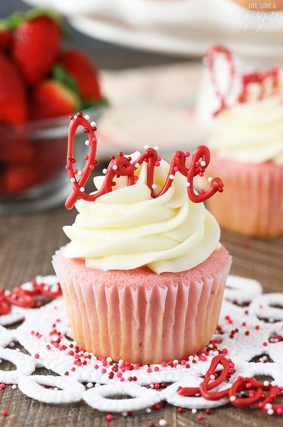 strawberry cupcakes with vanilla icing and a "love" cupcake topper.