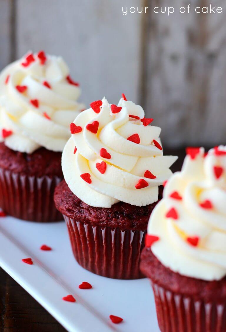 red velvet cupcakes with white icing and red heart sprinkles.