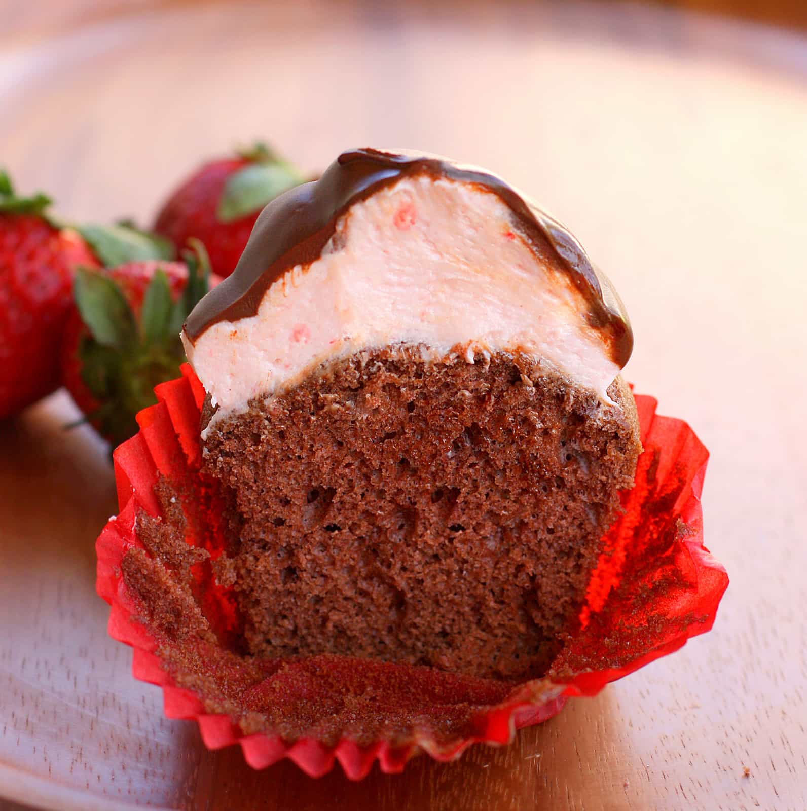 chocolate cupcake cut in half to show thick strawberry frosting on top.