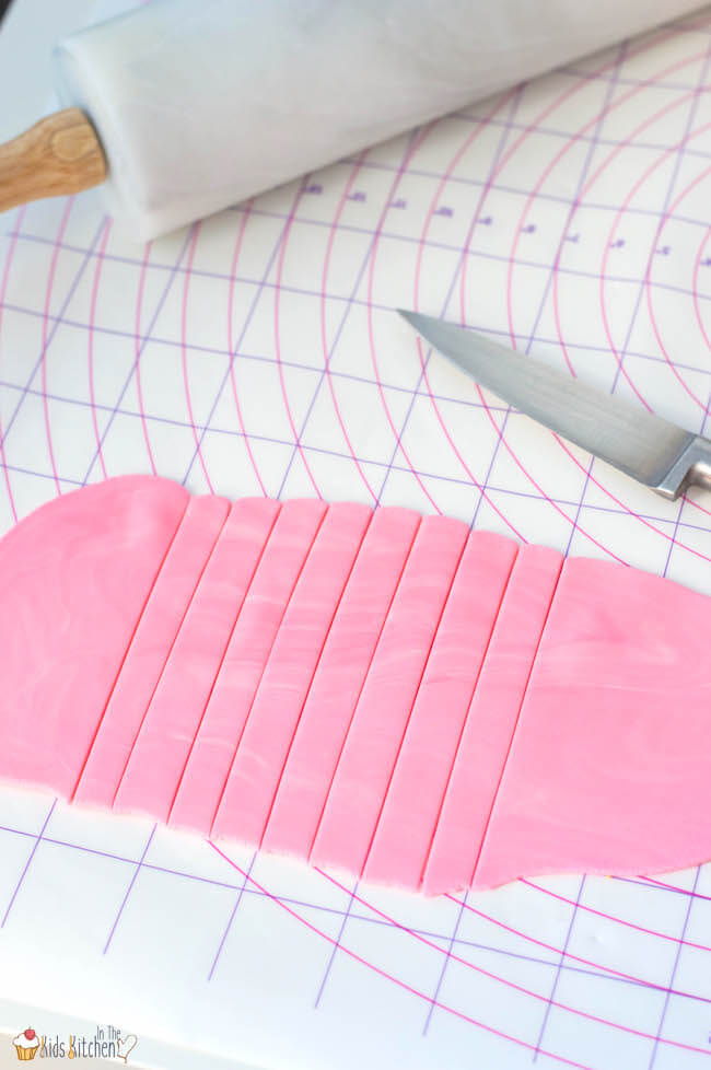 Cutting pink fondant icing into strips