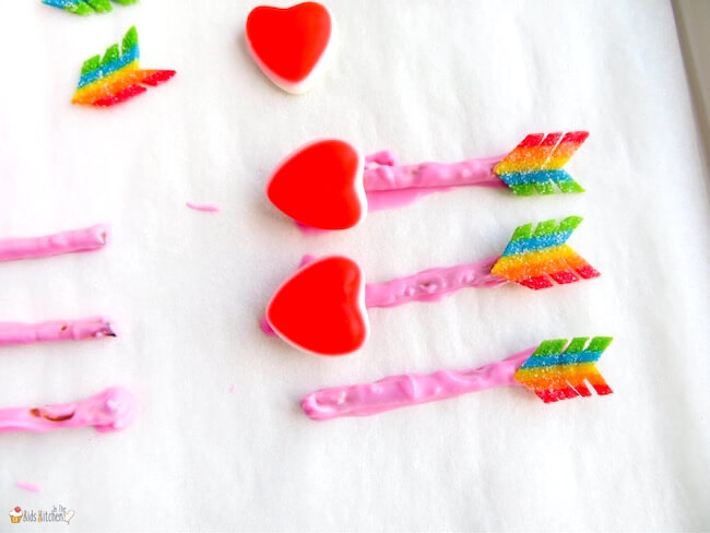 adding heart candies to pretzel sticks to look like an arrow