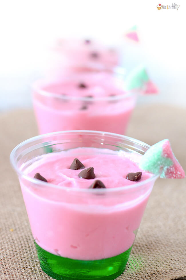 watermelon pudding cups with pink pudding on top of green jello