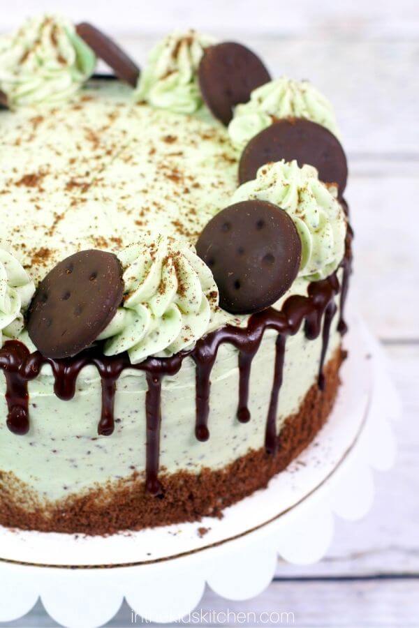 a round layer cake with mint green frosting, chocolate ganache, and thin mint cookies on top