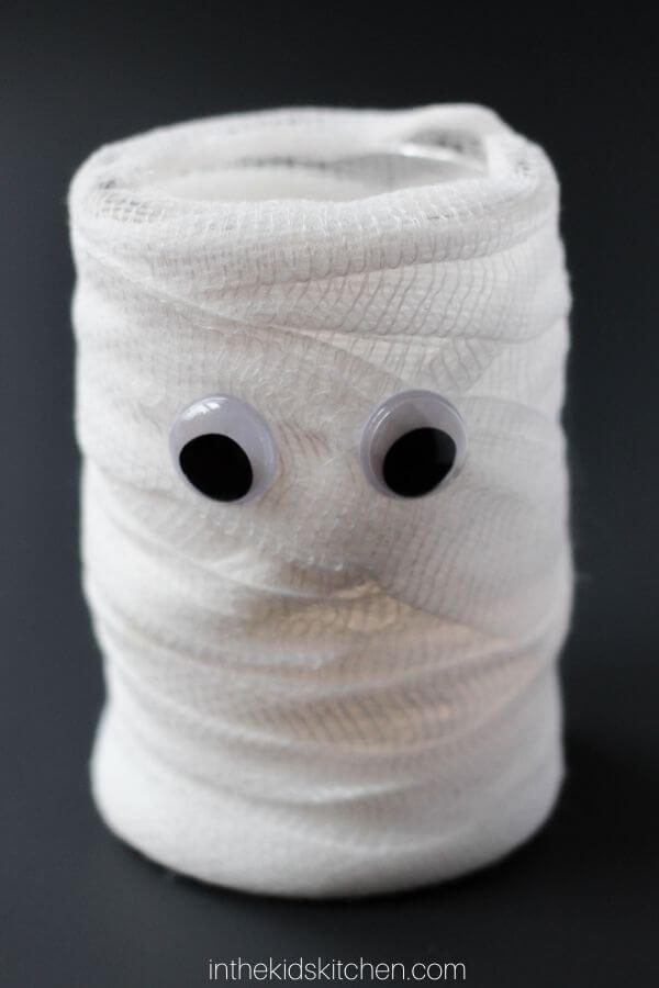 a mason jar wrapped in gauze with google eyes to look like a mummy