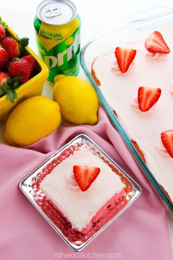 top down view of a strawberry cake with basket of berries and can of Sprite