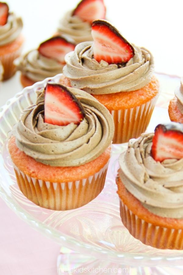 platter of strawberry cupcakes topped with chocolate frosting and half of a chocolate covered strawberry.