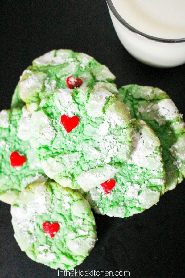 green crinkle cookies with a red heart sprinkle on each.