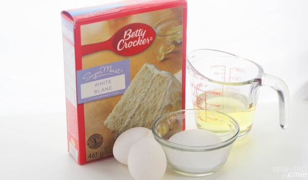 cake mix sugar cookie ingredients: a box of cake mix, cup of oil, eggs, and bowl of sugar