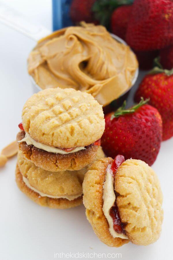 peanut butter and jelly filled cookies with cup of peanut butter in background