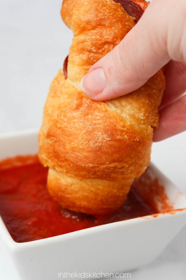 dipping a pizza roll in sauce.
